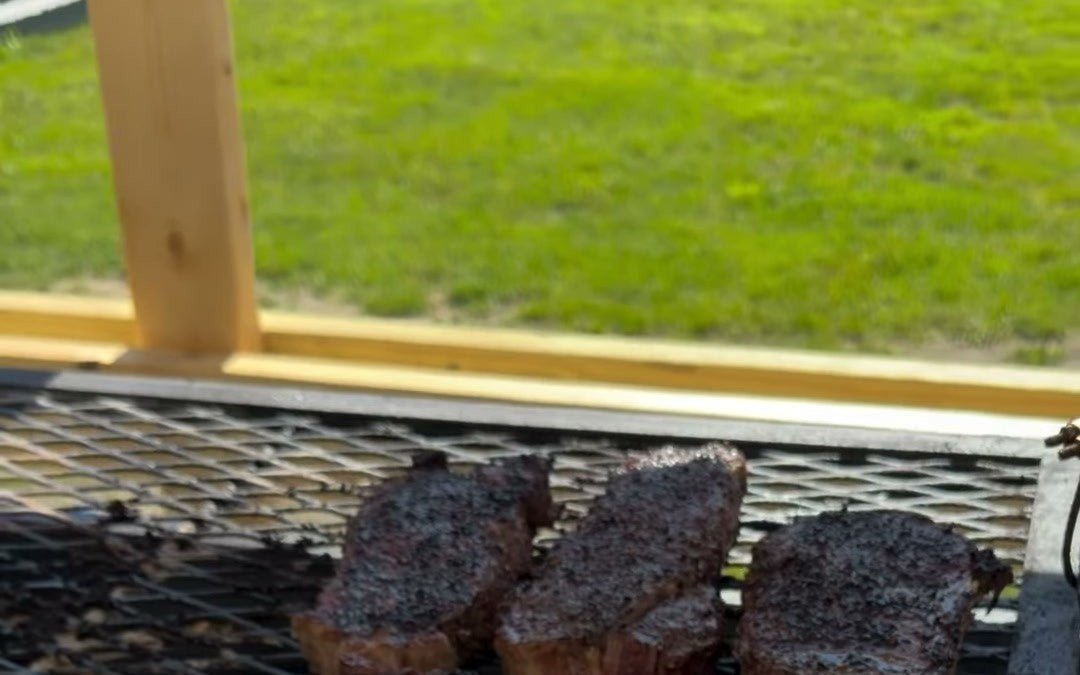 Two rubbed steaks on the grate over charcoal, the kind of cook every question below is about.
