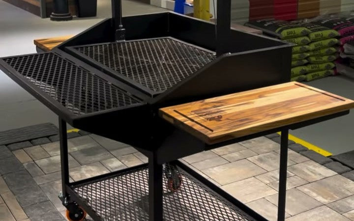 The shop's own custom Santa Maria grill on the sales floor: crank wheel, expanded metal grate, and wood side shelves.