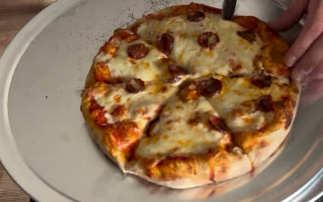 A sliced Buffalo-style cup-n-char pepperoni pizza fresh out of the pellet grill pizza oven.